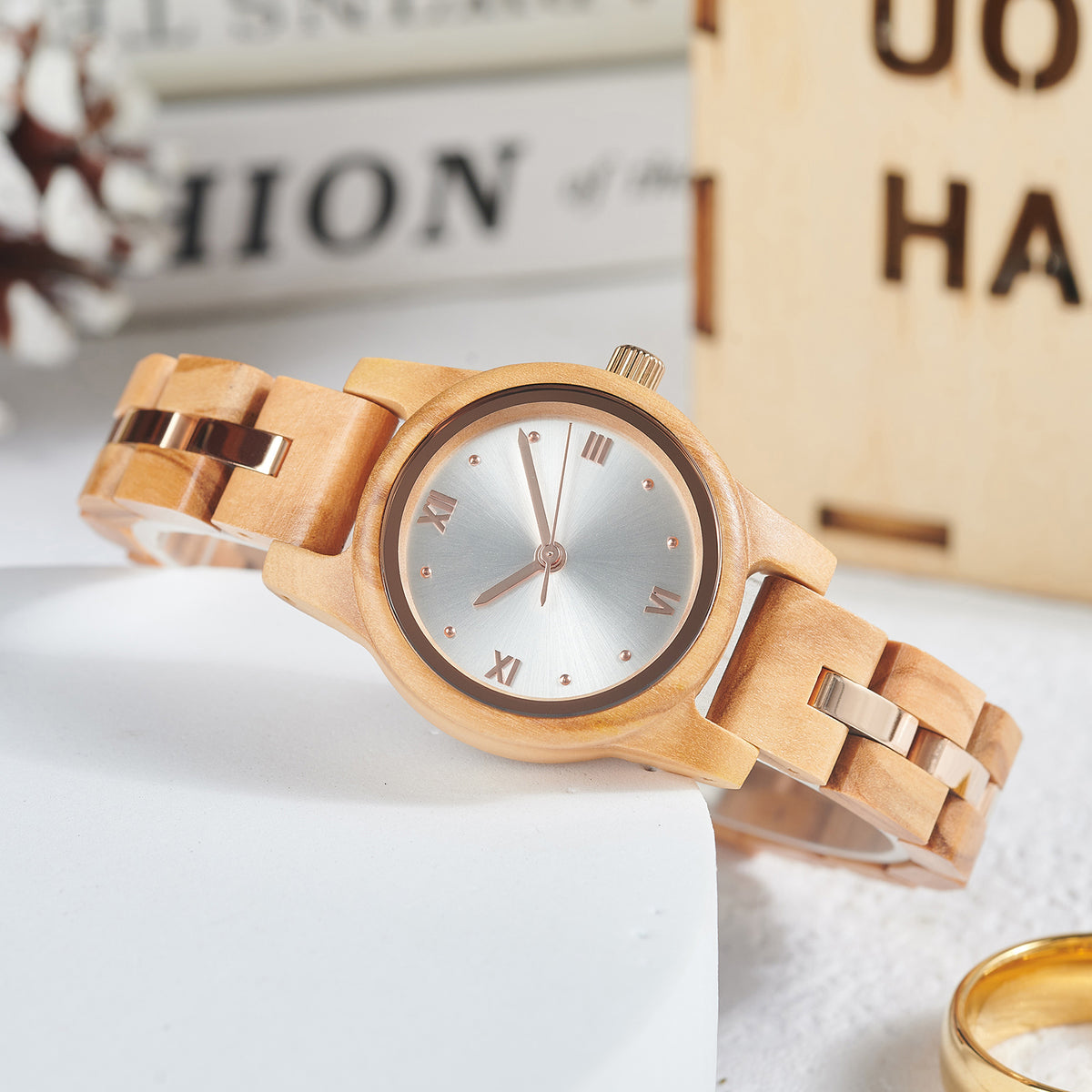 A sophisticated women's wooden watch featuring a silver dial, rose gold accents, and Roman numerals, presented against an elegant white background with a gold ring to highlight its refined and stylish design.