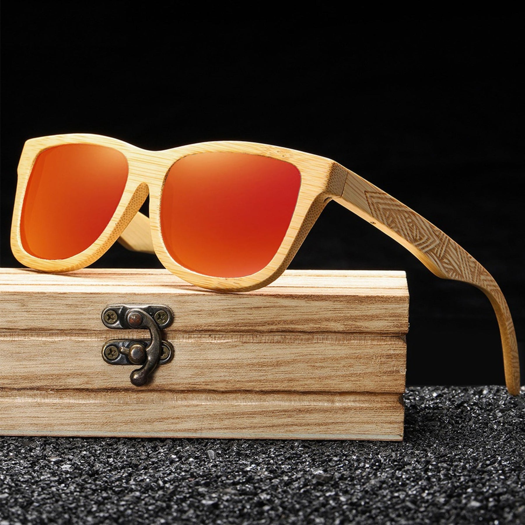 Orange lens engraved arms bamboo sunglasses standing on wooden table