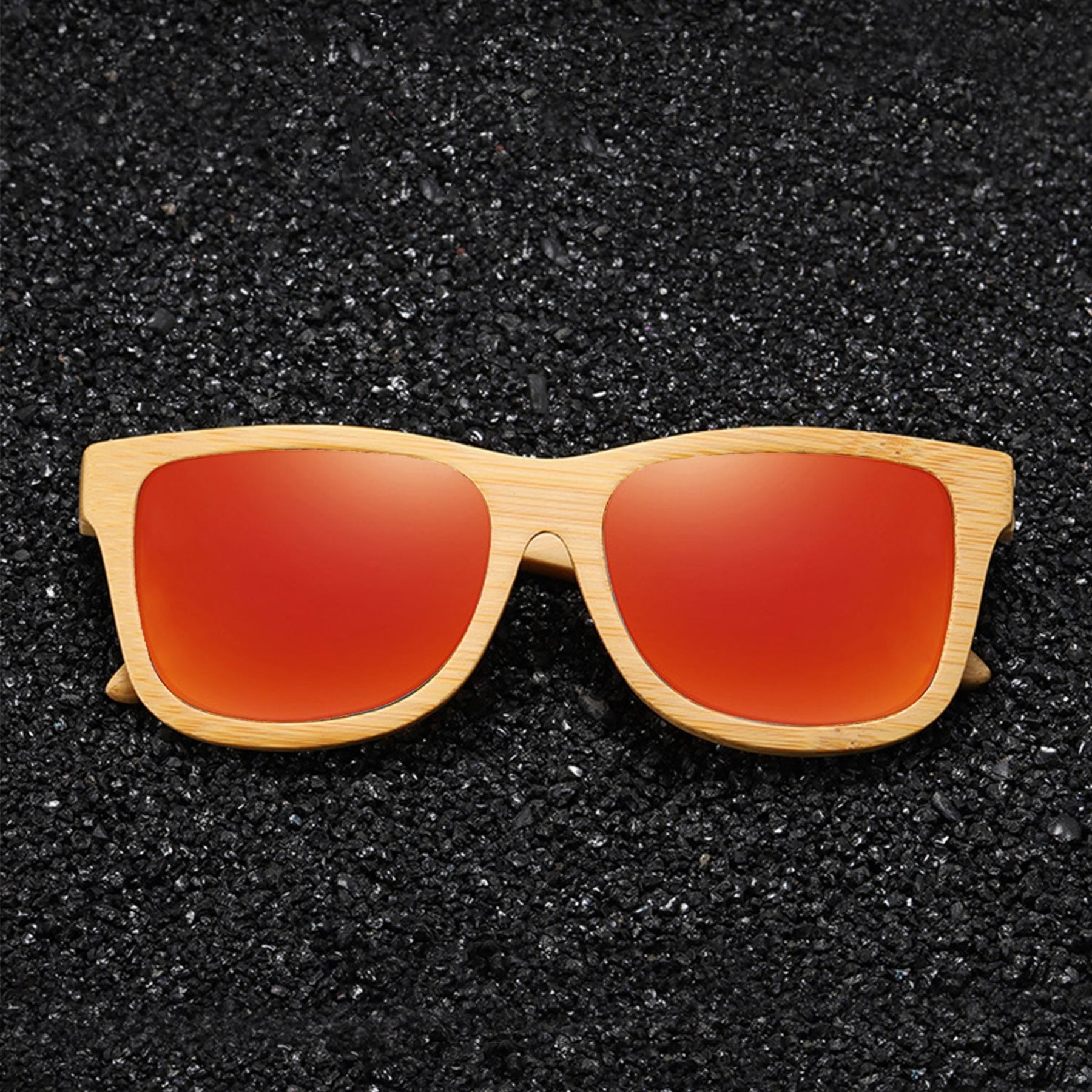 Orange polarized lens bamboo sunglasses on black sandy ground