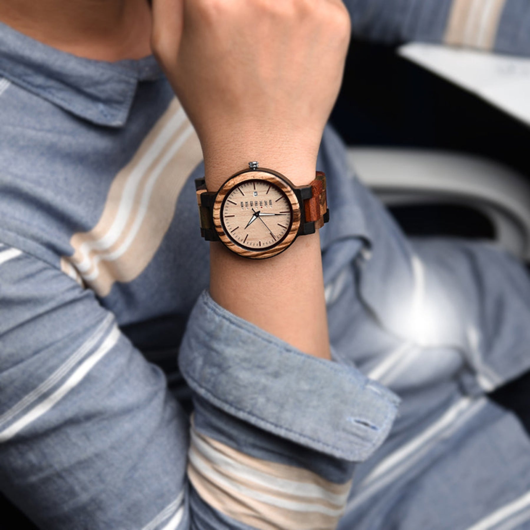 A man wearing an ebony and colorful strap watch with maple face