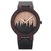 A unique dark wooden watch featuring a runic symbol bezel, forest silhouette dial, black leather band, and gold-tone hands, displayed against a white background.