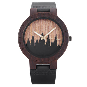 A unique dark wooden watch featuring a runic symbol bezel, forest silhouette dial, black leather band, and gold-tone hands, displayed against a white background.