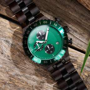 A detailed view of a men's dark wooden chronograph watch with green accents, displayed on a wooden surface to emphasize its craftsmanship and sophisticated design.