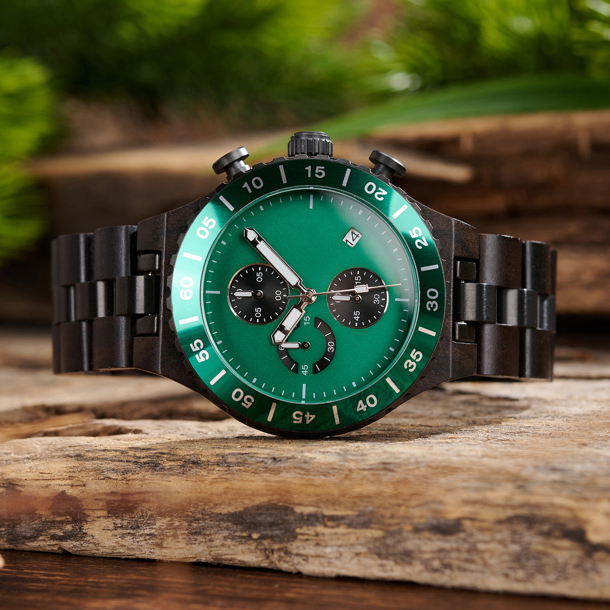 A stylish men's dark wooden chronograph watch with green accents, showcased amidst lush greenery to highlight its sophisticated and rugged design.