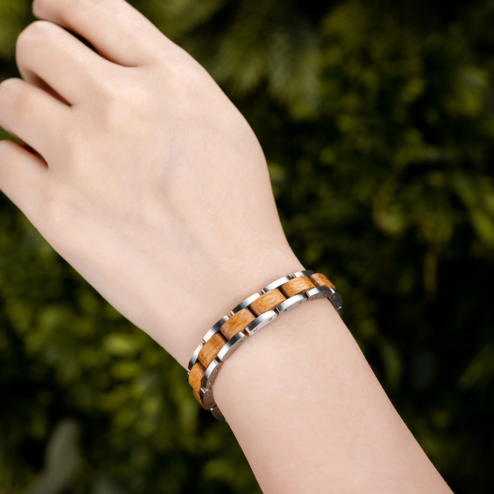 Men's wooden bracelet with stainless steel links on wrist, nature background. Stylish, rustic modern design, perfect for masculine, outdoor-inspired accessory lovers.