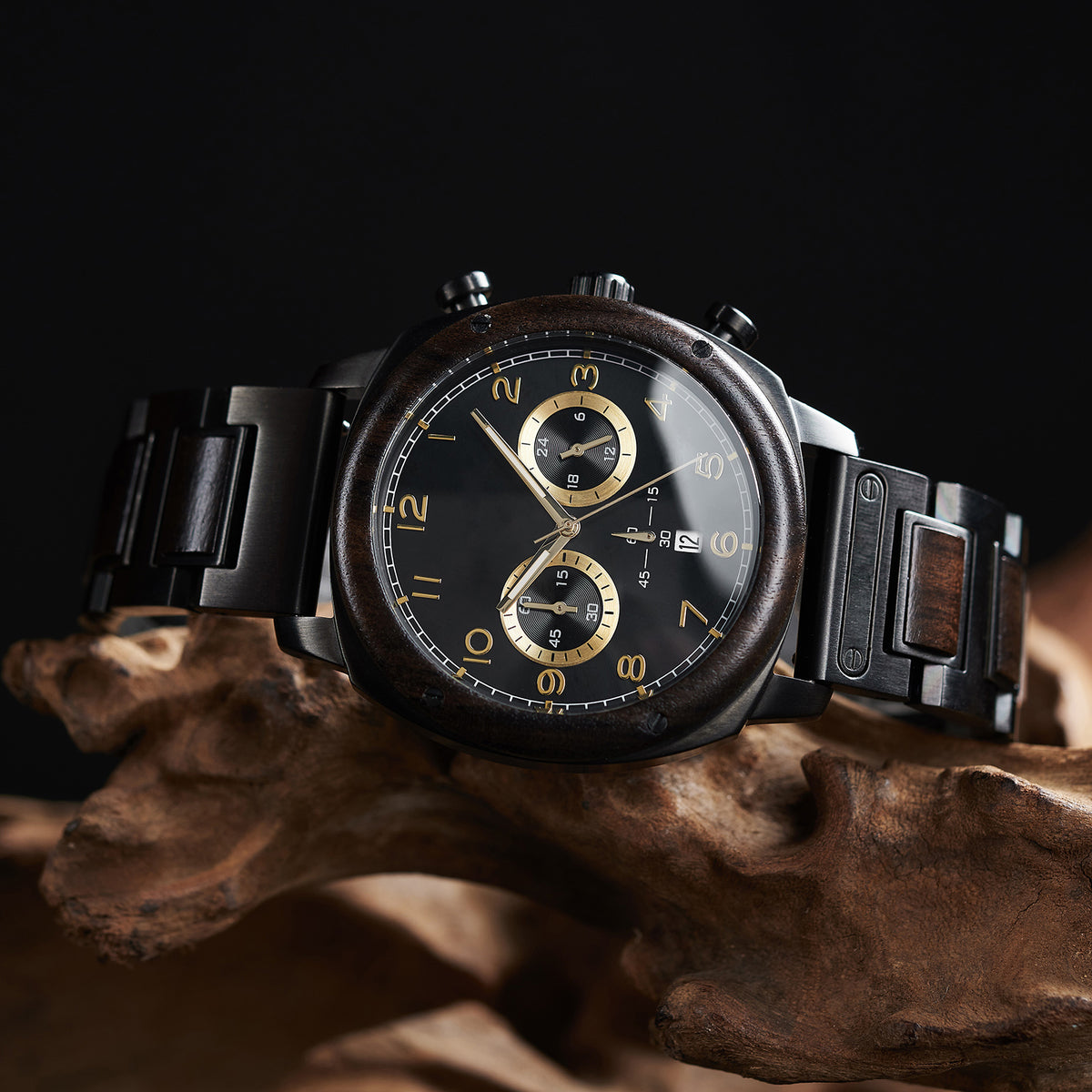 A stylish men's wooden chronograph watch with a black dial and gold accents, showcased on natural wood to highlight its sophisticated and rugged design.
