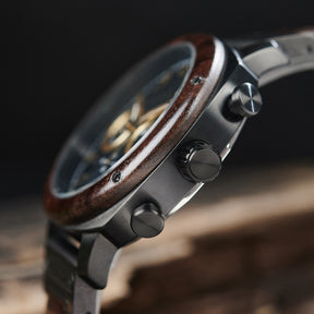 A detailed side view of a men's wooden chronograph watch with a black dial and gold accents, emphasizing the craftsmanship of its wooden bezel and metallic components.