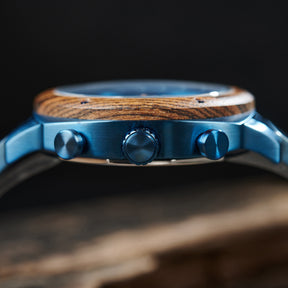 A detailed side view of a men's wooden chronograph watch with a blue dial, emphasizing the craftsmanship of its wooden bezel and metallic accents.