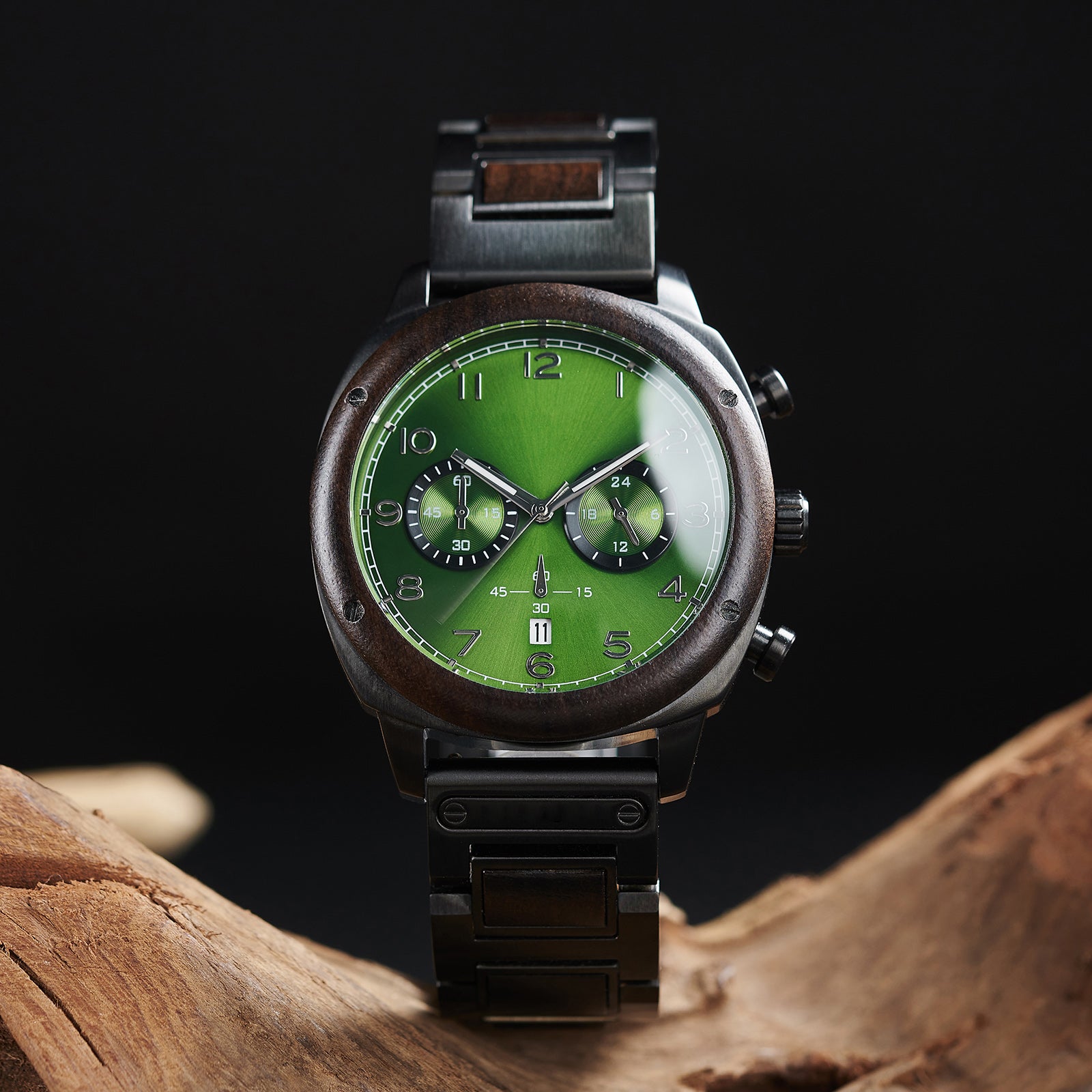 A stylish men's wooden chronograph watch with a green dial and dark accents, showcased on natural wood to highlight its sophisticated and rugged design.