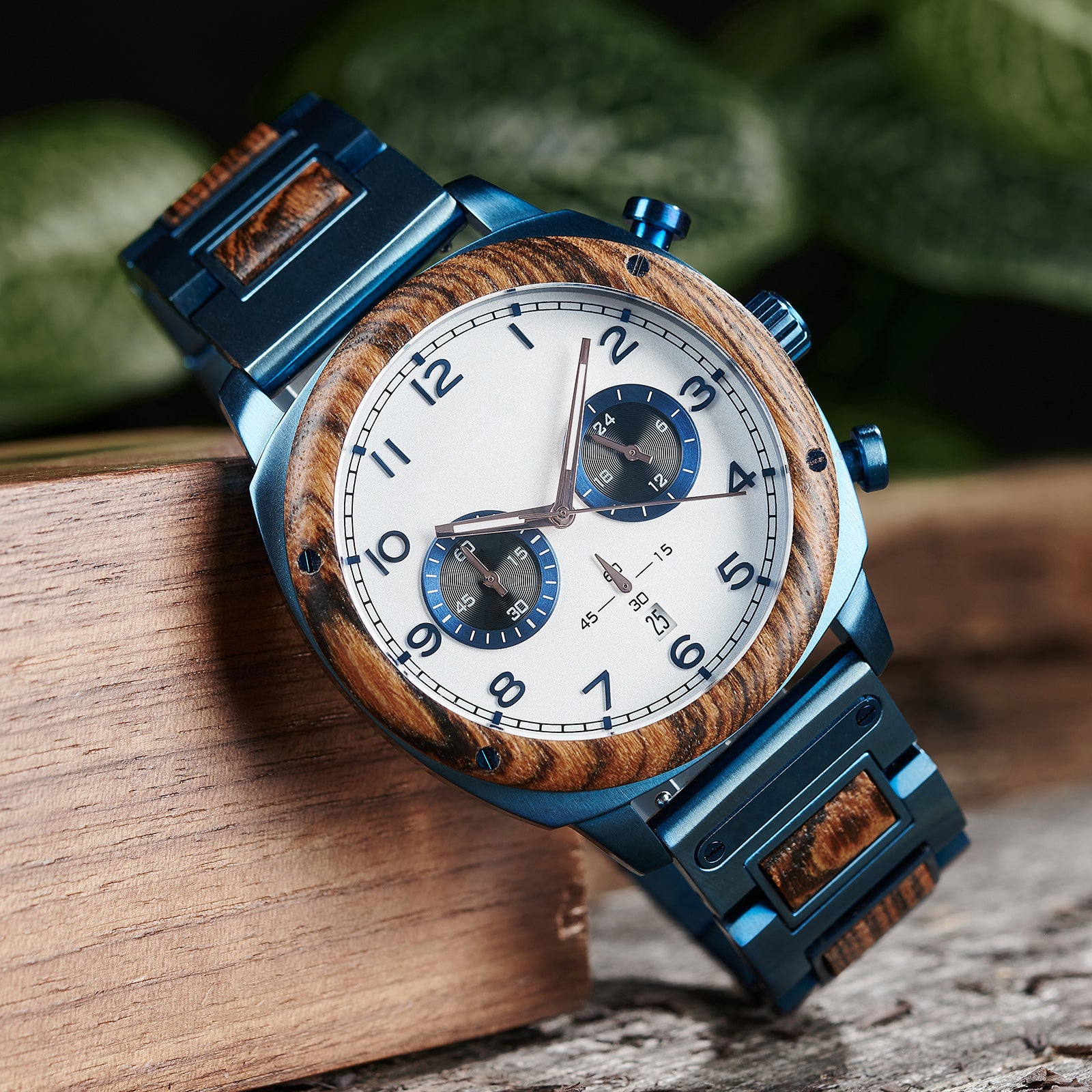 A stylish men's wooden chronograph watch with a white dial and blue accents, showcased on natural wood to highlight its sophisticated and rugged design.