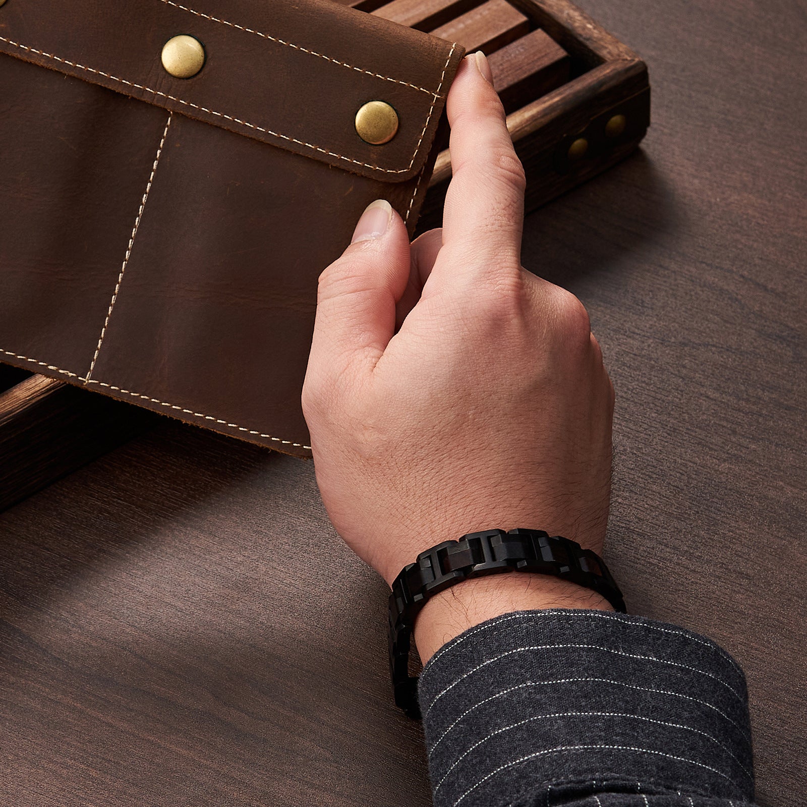 Man wearing a black stainless steel and ebony wood bracelet, showcasing a tough and stylish look for men's jewelry collection.