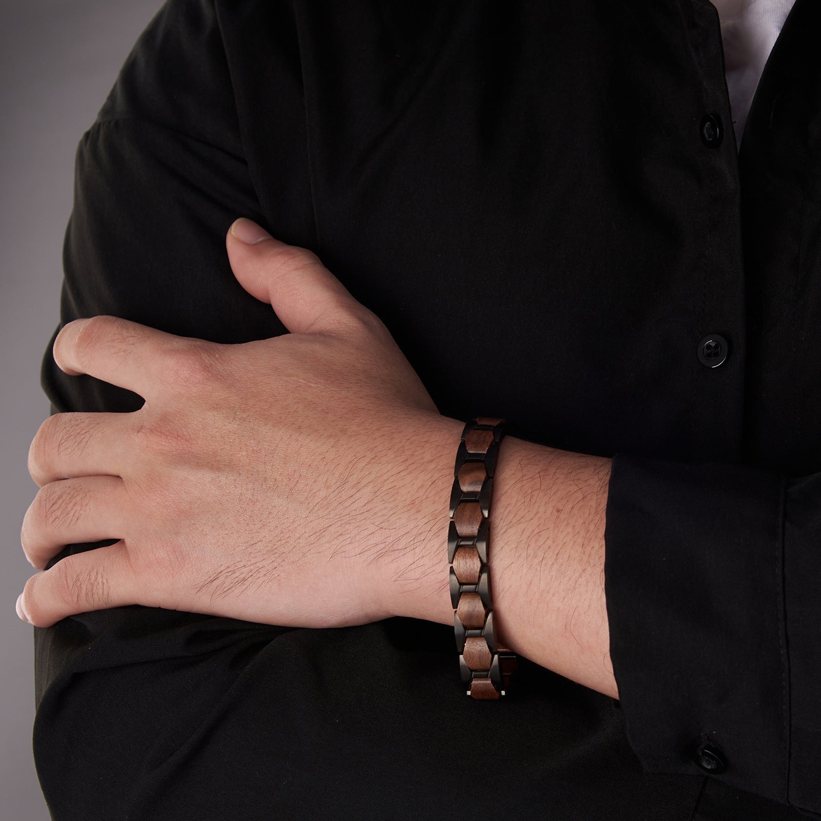 Man wearing a black stainless steel and walnut wood bracelet, showcasing a sophisticated and masculine look for men's jewelry style.