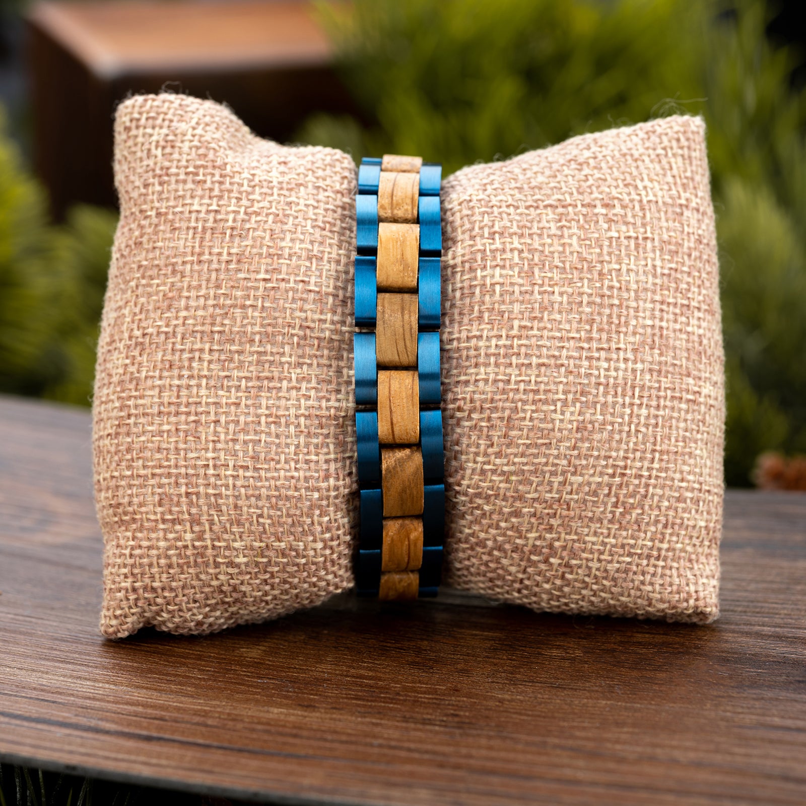 Men's fashionable bracelet with blue stainless steel and natural oak wood links, displayed on a rustic burlap pillow, ideal for men's accessories and style.