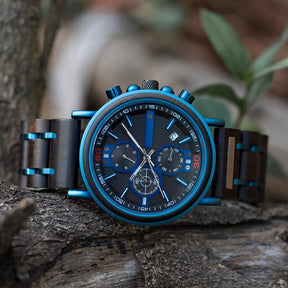A stylish men's chronograph watch featuring blue metallic accents, a dark dial with multiple sub-dials, and a mixed-material band, presented on a rustic wood background to highlight its sporty and sophisticated design.