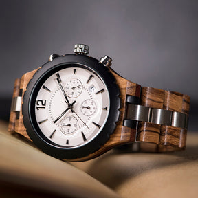 A men's chronograph watch featuring a combination of light wood and stainless steel bands, a white dial with multiple sub-dials, metallic hour markers, and a black bezel, positioned on a neutral surface.
