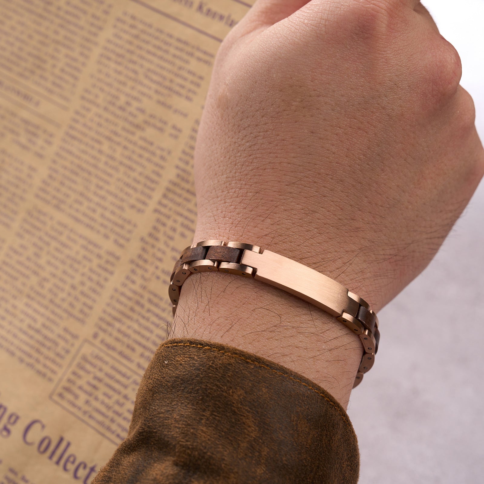 Men wearing a sophisticated bracelet with rose gold stainless steel and natural walnut wood links, paired with a brown sleeve, ideal for men's fashion and everyday accessorizing.