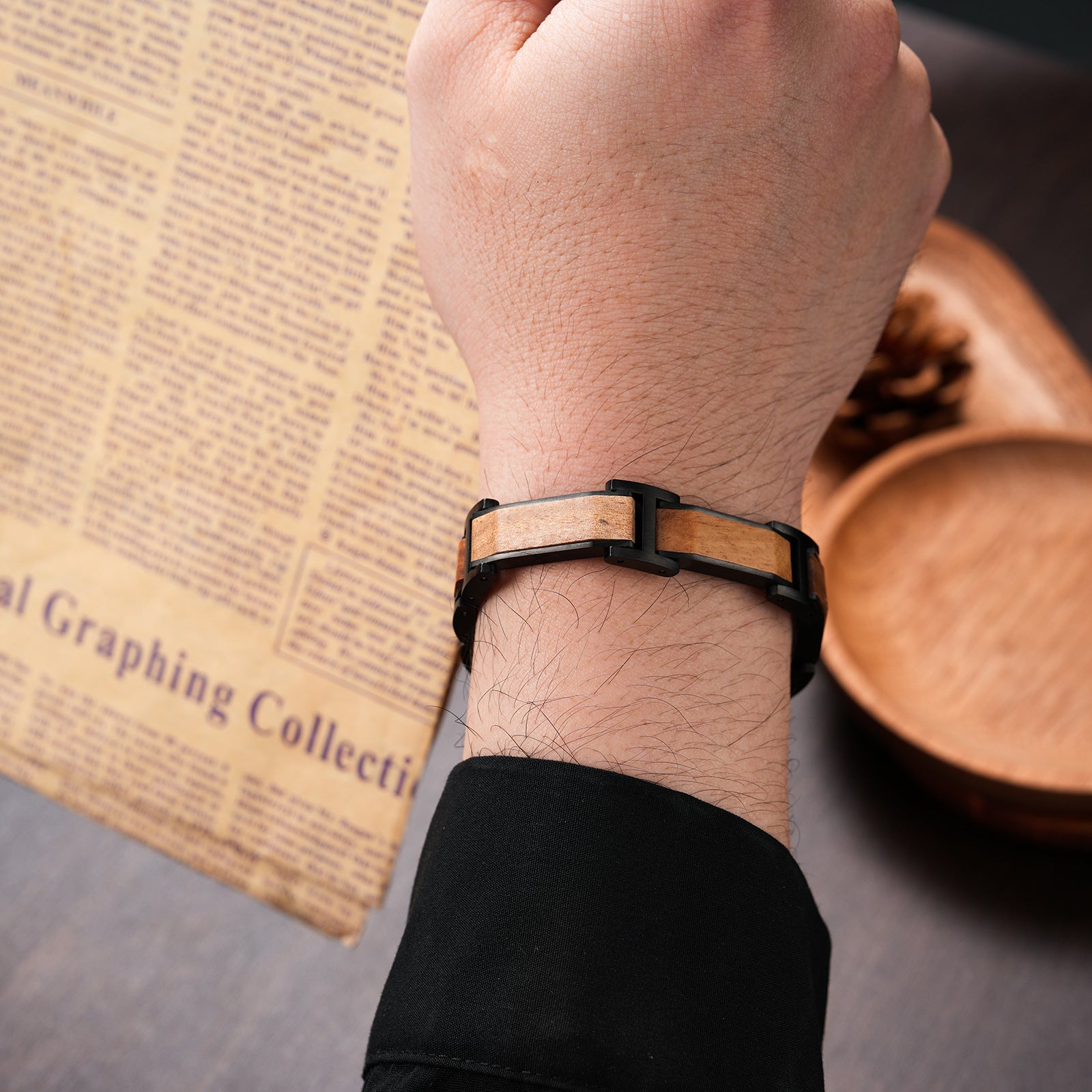 Men's bracelet made of black stainless steel and walnut wood, shown on a man's wrist, stylish accessory for men, featuring a unique wood and metal design.