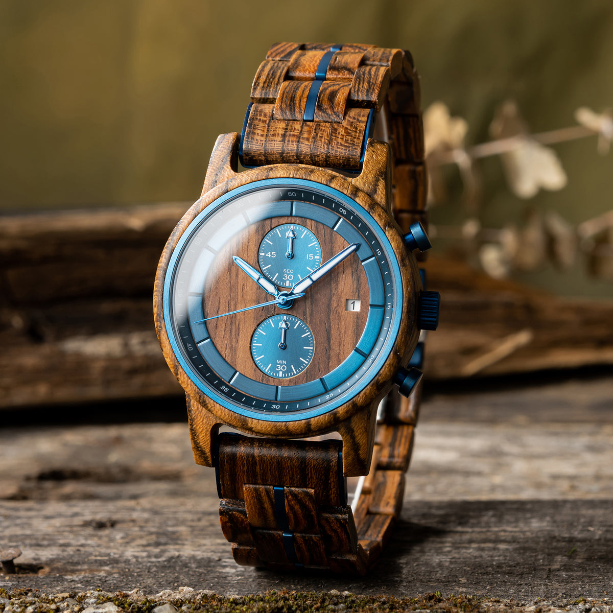 A stylish men's wooden chronograph watch featuring a wood dial, blue accents, and multiple sub-dials, presented against a rustic wood background to highlight its sophisticated and natural aesthetic.