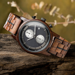 A stylish men's wooden chronograph watch featuring a dark gray dial, multiple sub-dials, and a brown wood band, presented against a rustic wood background to highlight its sophisticated and natural aesthetic.
