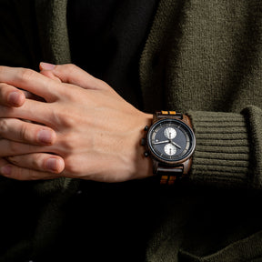 A stylish men's wooden chronograph watch with a two-tone wood band, showcased on a wrist paired with an olive green sweater, highlighting its sophisticated and versatile aesthetic in a lifestyle context.