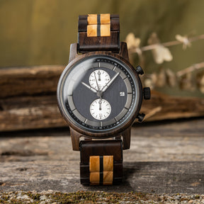 A stylish men's wooden chronograph watch featuring a two-tone wood band, dark gray dial, multiple sub-dials, and a date function, presented against a rustic wood background to highlight its sophisticated and natural aesthetic.
