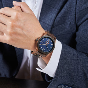 A sophisticated men's wooden watch featuring a blue dial, showcased on a wrist wearing a navy suit in a professional setting, highlighting its elegant and polished aesthetic.
