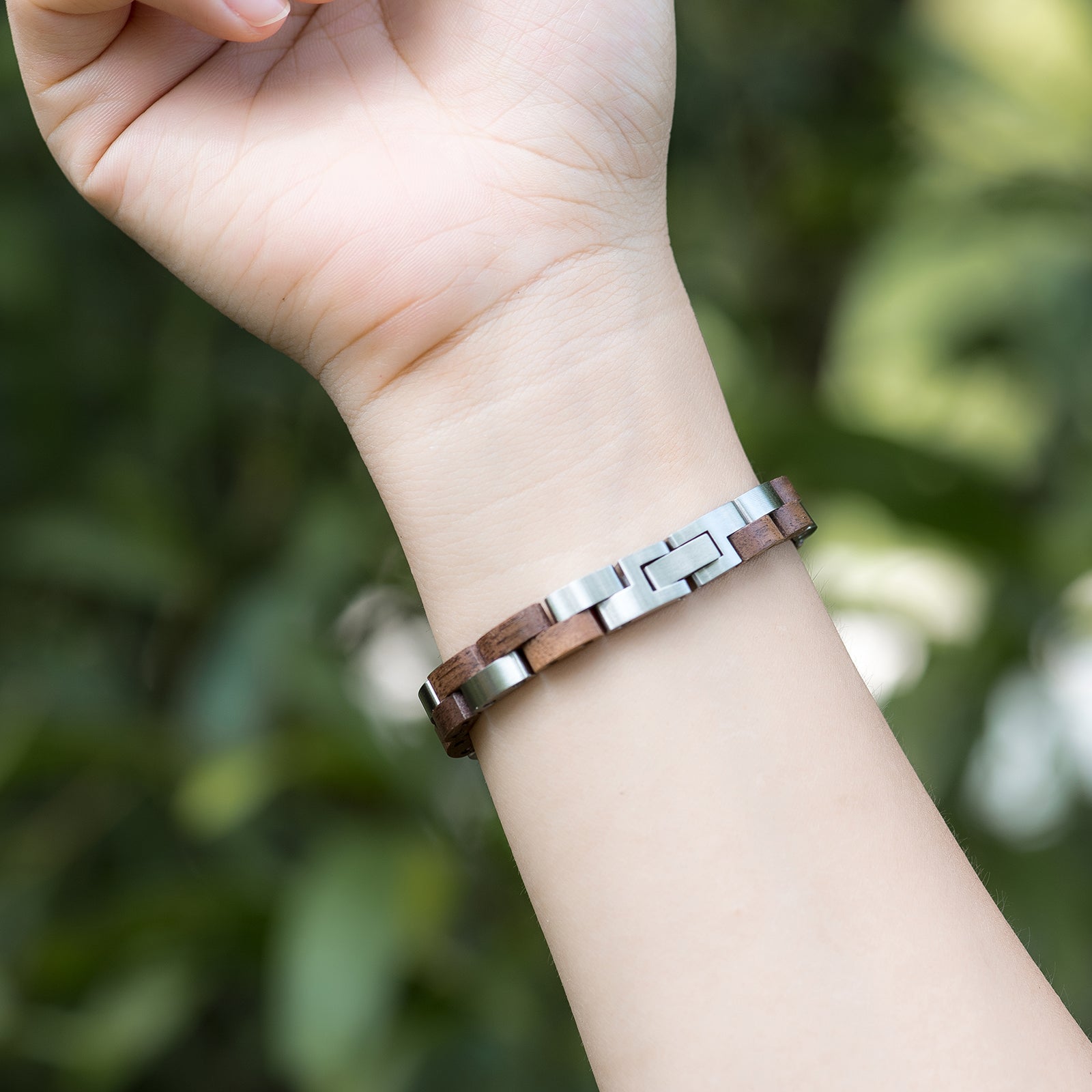 Women's wooden bracelet with stainless steel links on wrist, boho-chic style. Nature-inspired, stylish feminine accessory, perfect for daily wear & bohemian looks.