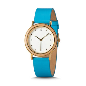 A minimalist women's watch with a wooden-accented bezel, white dial, gold-tone details, and a blue leather band, presented against a white background.