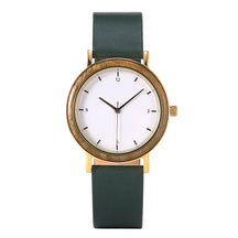 A minimalist women's watch featuring a wooden-accented bezel, white dial, gold-tone details, and a dark green leather band, displayed against a white background.