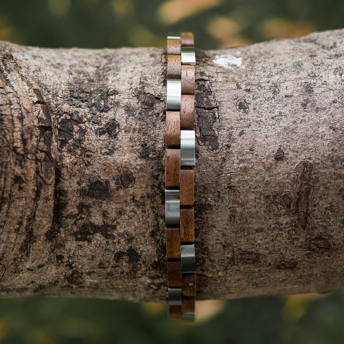 Women's bracelet with wood and stainless steel links, placed on tree bark. Rustic yet modern design, perfect for nature-inspired, stylish accessories lovers.