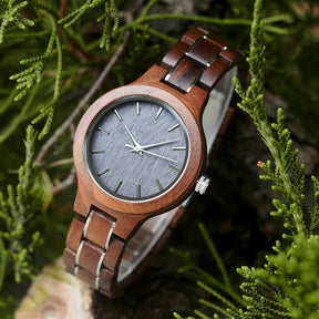A stylish women's walnut watch with silver-tone accents, showcased amidst lush greenery to highlight its natural wood grain and elegant design.