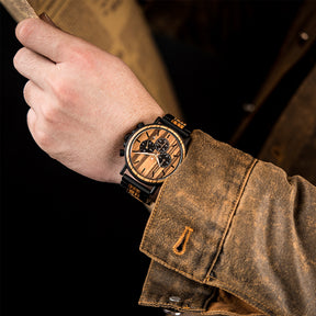 A man wearing a black metal and zebrawood chronograph watch with zebrawood face